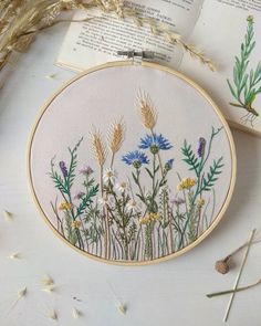 an embroidery pattern with wildflowers and grasses on it, next to two books