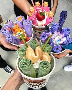 people holding up three cups filled with different types of desserts and pastries on top of each other