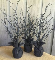 two black vases with branches in them are sitting on a cloth covered tablecloth