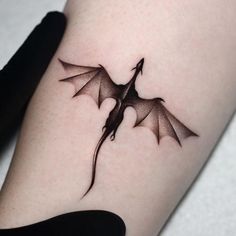 a small black dragon tattoo on the right thigh and lower leg, it appears to be flying in the air