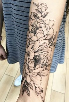 a woman's arm with flowers and leaves tattooed on the wrist, in black ink