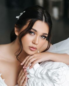 a woman in a wedding dress posing with her hands on her chest and looking at the camera