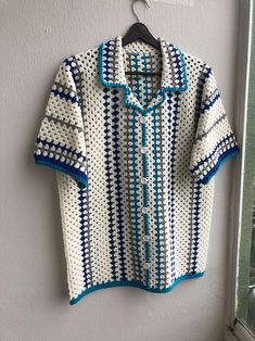 a crocheted shirt hanging on the wall