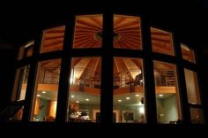 the inside of a house at night with lots of windows and lights shining in it