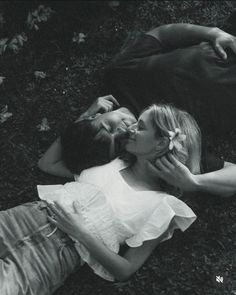 black and white photograph of two people laying on the ground with their heads touching each other