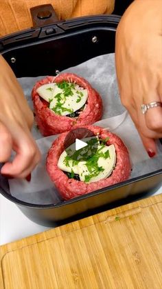 two women are preparing food in a pan on the stove top and one woman is cutting it into small pieces