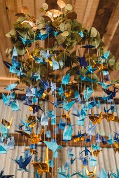 a chandelier made out of blue and gold origami birds hanging from the ceiling