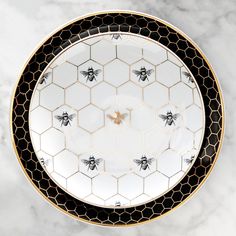 a white plate with black and gold honeycombs on it, sitting on a marble surface