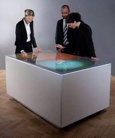 two business people looking at a display on a wooden floor in front of a gray wall