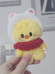 a yellow stuffed animal with a red scarf around it's neck is held up