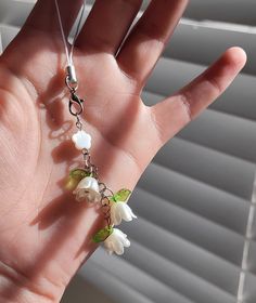 a hand is holding some white flowers and green leaves in the sunlit window sill