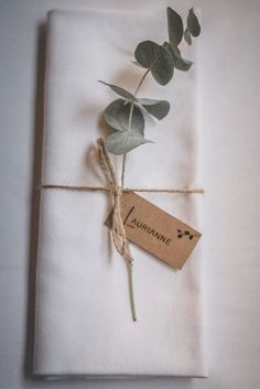 a white napkin with a tag tied to it and a single flower on top of it