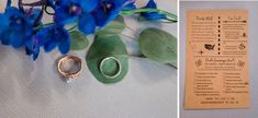 two wedding rings and some blue flowers on a white table cloth next to a menu