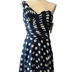 a dress on a mannequin with white polka dots and an asymmetrical neckline