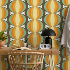 a desk with a lamp and a book on it in front of a wallpaper