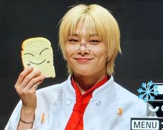 a person holding a piece of bread with a smiley face drawn on it and wearing a red tie