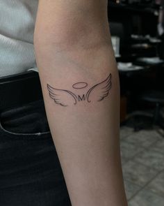 a woman's arm with an angel wing tattoo on the left side of her arm