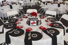 the table is set with black and white linens, red roses, and silverware