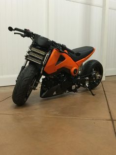 an orange motorcycle parked in front of a white wall