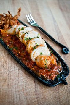 some food is laying out on a black plate with a fork and knife next to it