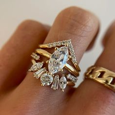 a woman's hand with two gold rings and an oval shaped diamond ring on it