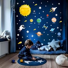 a young boy sitting on the floor in front of a wall with space decals