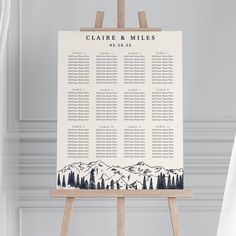 a wooden easer with a seating chart on it and mountains in the back ground