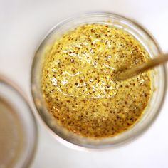 a glass jar filled with liquid sitting on top of a white table next to a wooden spoon