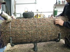 two men working on a large piece of hay