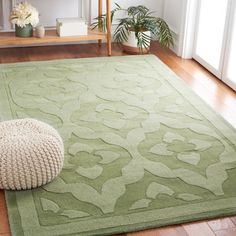 a green rug on the floor next to a white poufce footstool