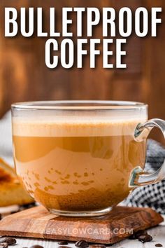 a glass cup filled with coffee sitting on top of a wooden cutting board next to bread