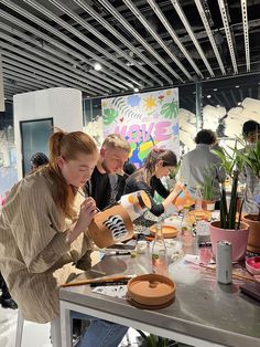 a group of people sitting around a table with food on it and plants in the background