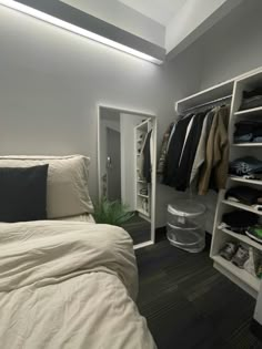 a white bed sitting next to a closet filled with clothes