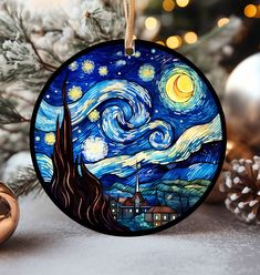 a christmas ornament with a starry night painting on it and pine cones in the background