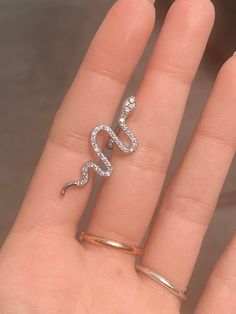 a person's hand holding a ring with a snake design on the middle of it