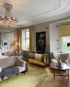 a bedroom with a bed, couch and chandelier hanging from the ceiling in front of two windows