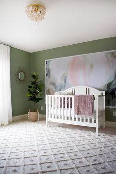 a baby's room with a large painting on the wall and a white crib