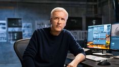 a man sitting at a desk in front of two computer monitors