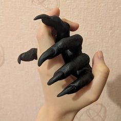 two hands holding fake black nails on top of each other