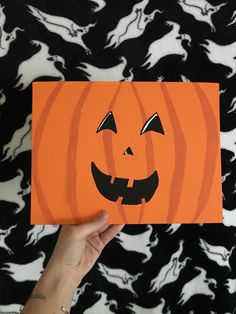 someone is holding up an orange card with a jack - o'- lantern on it