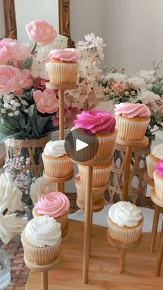 cupcakes are arranged on wooden stand in front of flowers and vase with mirror