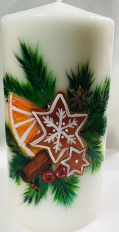 a lit candle decorated with an image of a gingerbread cookie and pine cones on it