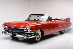 an old red convertible car parked in a white room