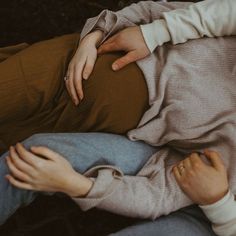 a pregnant woman laying on the ground with her belly wrapped around her husband's waist