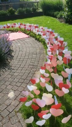 some pink and white flowers are in the middle of a brick path with green grass