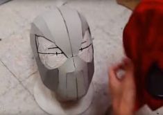 someone is making a mask out of paper on the floor and it looks like he's going to die