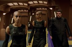 two men and a woman walking down a hallway in sci - fi outfits, one wearing sunglasses