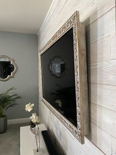 there is a vase with flowers on the table in front of the tv and mirror