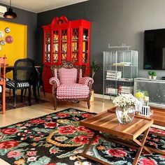 a living room filled with furniture and a red china cabinet next to a yellow wall