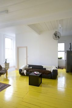 a living room with yellow floors and white walls